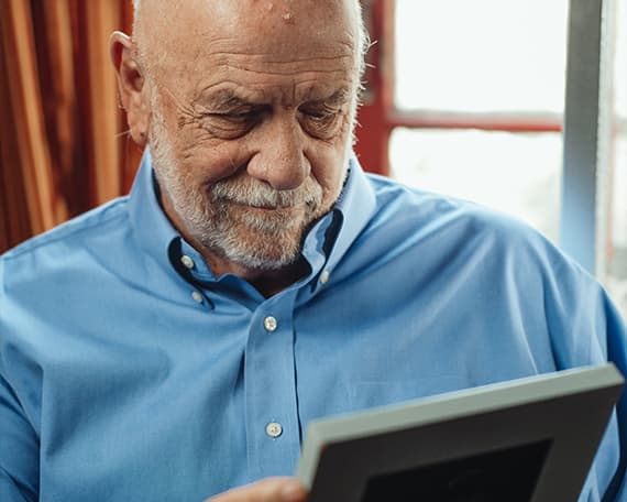 Man Reminiscing, Looking at Framed Photo