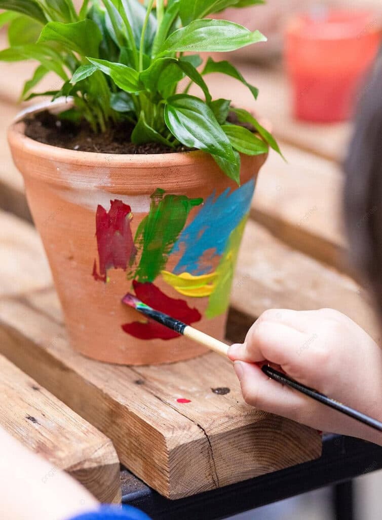 child painting a clay flower pot