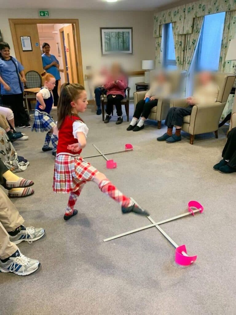 Children performing traditional Scottish dances for care home residents