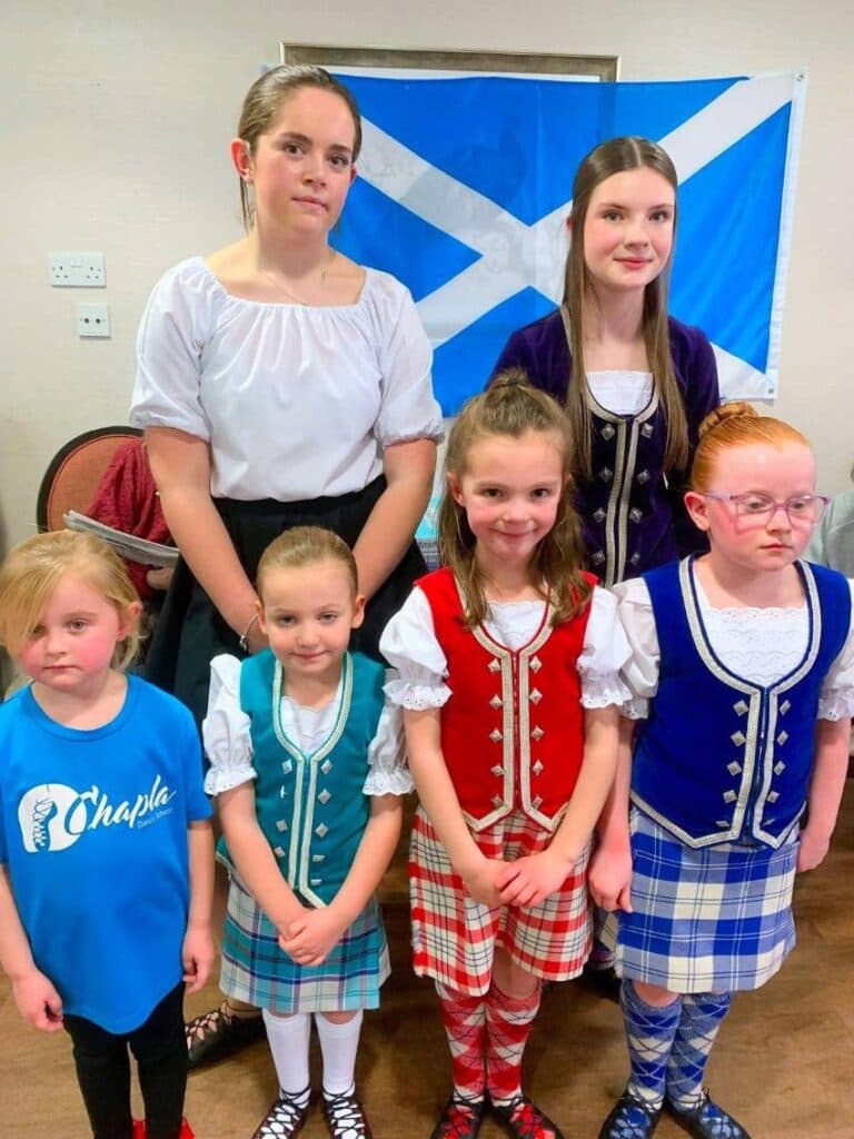 Scottish dance students standing in front of St Andrew's Cross